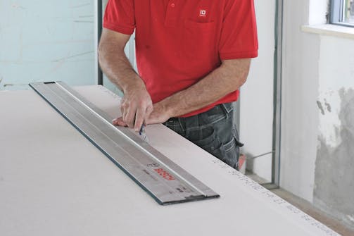 Sådan skæres gipsplader til: En føringsskinne er en rigtig god lineal til lange snit, og gummibagsiden gør, at den ikke skrider for dig. Sådan skæres gipsplader til: En føringsskinne er en rigtig god lineal til lange snit, og gummibagsiden gør, at den ikke skrider for dig.